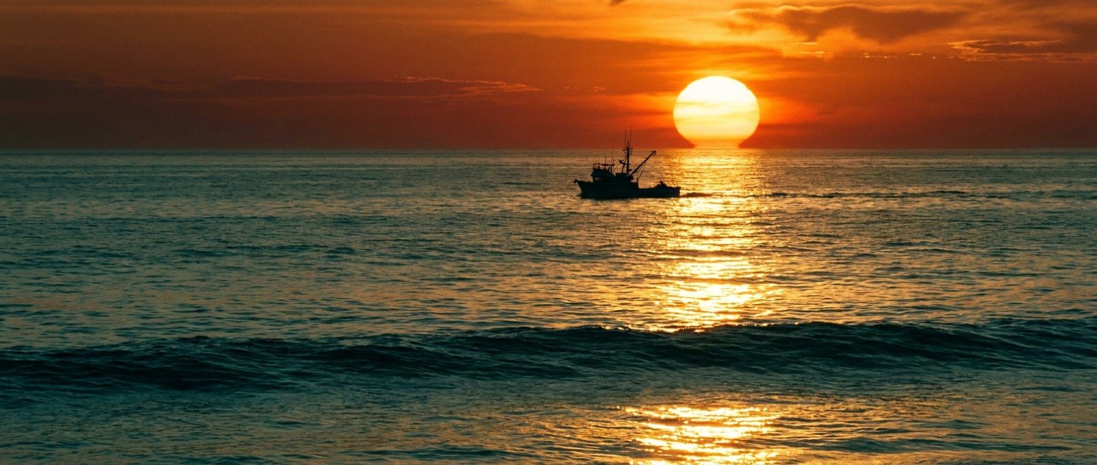 Fishing boat crossing the sunset light on the Pacific